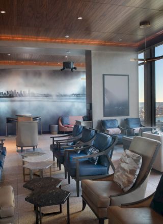 A stylish lounge with modern seating, large windows showcasing a waterfront view, and a mural of a city skyline on the wall ends the sentence.