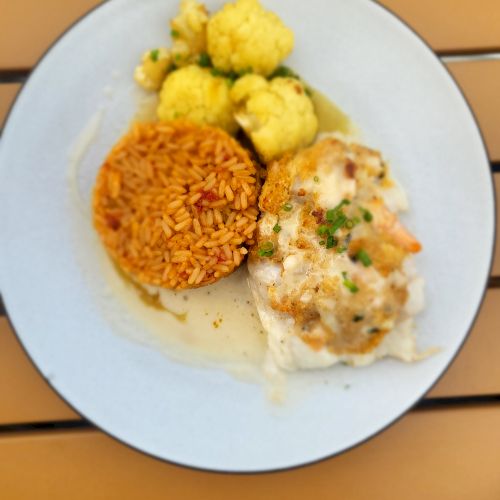 A plate of food featuring cauliflower florets, a serving of rice, and a portion of what appears to be fish with a creamy sauce and herbs.